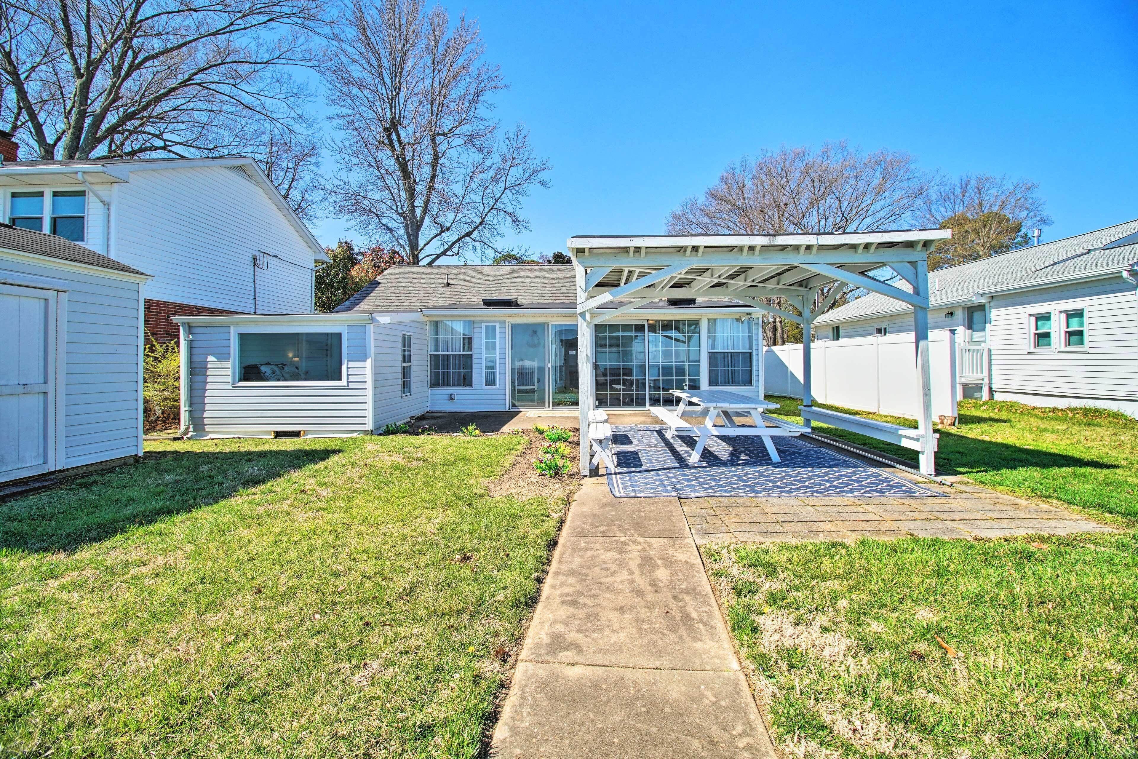 A backyard with a covered patio, a concrete pathway, and a small garden area.