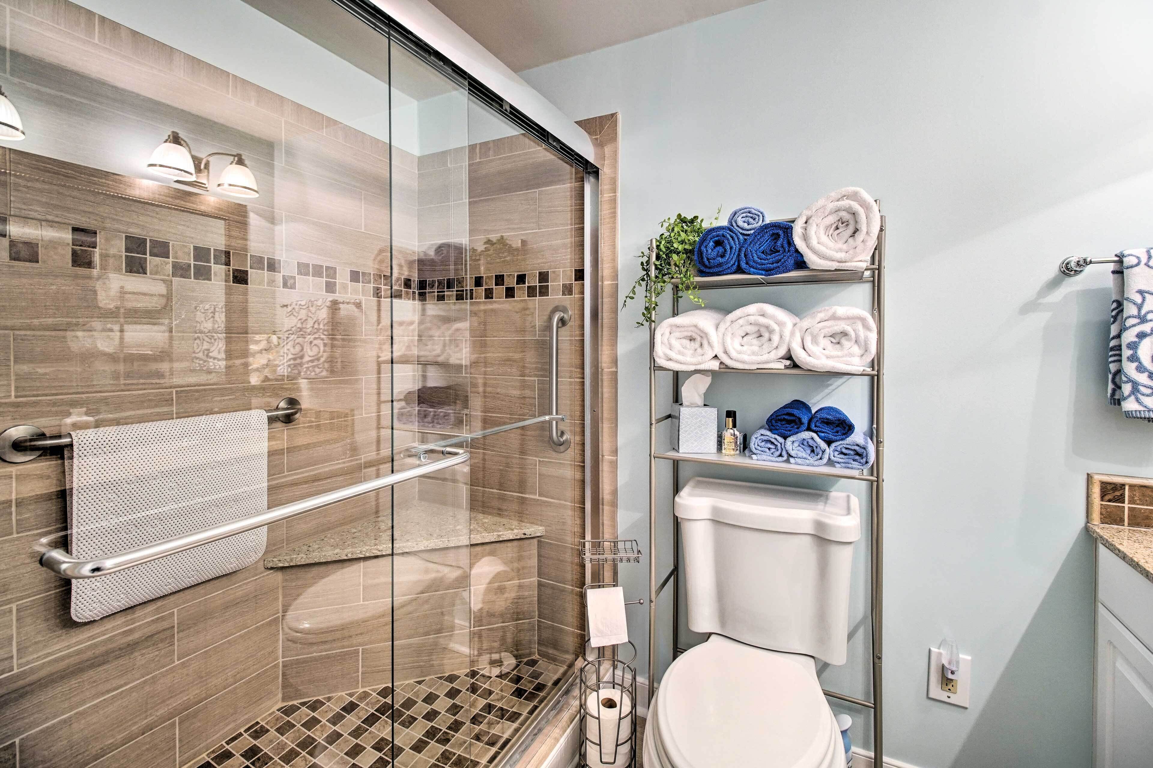 Un bagno moderno con doccia vetrata, un water e un portasciugamani con asciugamani ordinatamente piegati.