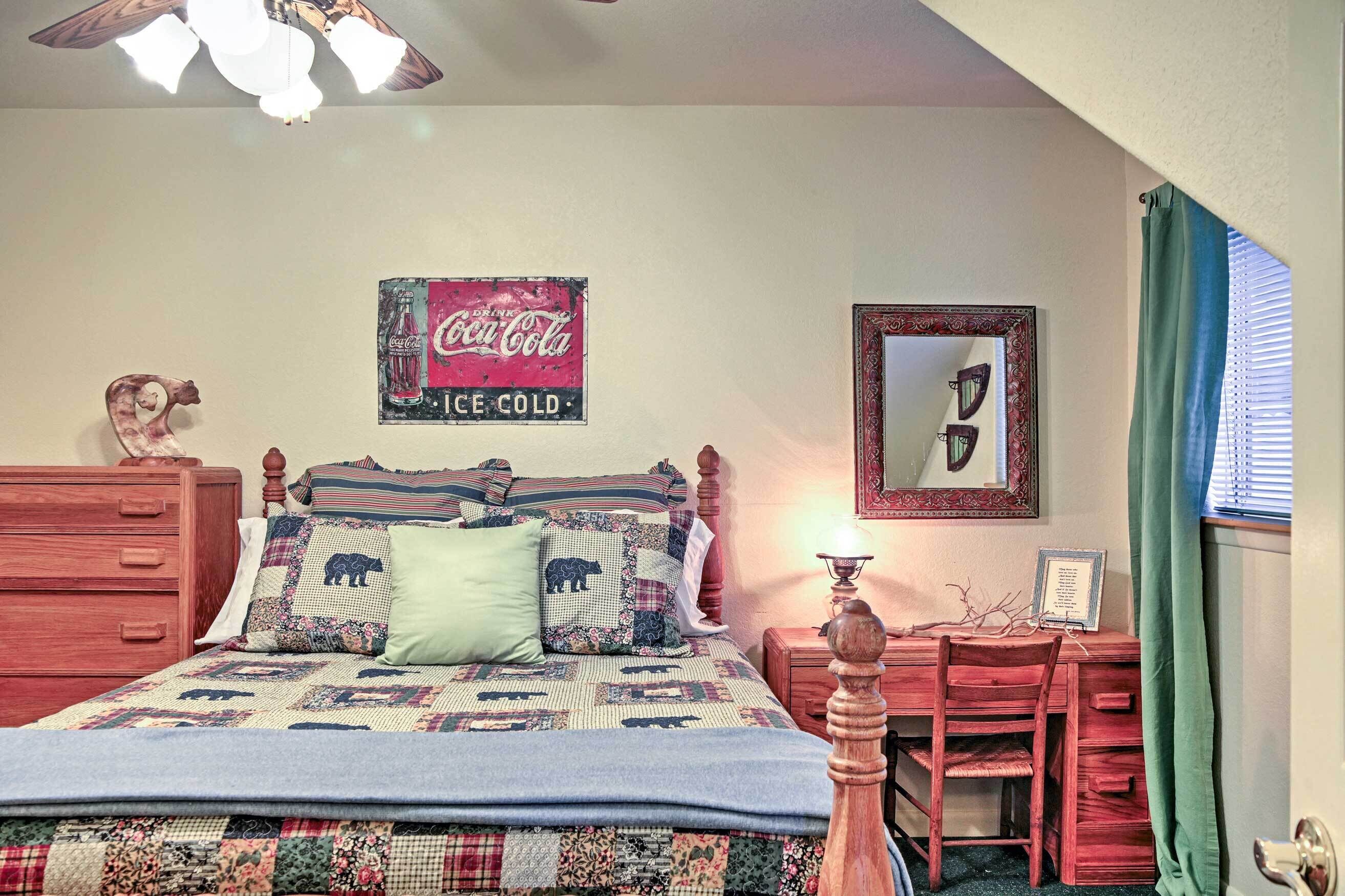 A bedroom with a bed, dresser, desk, and a Coca-Cola sign on the wall.