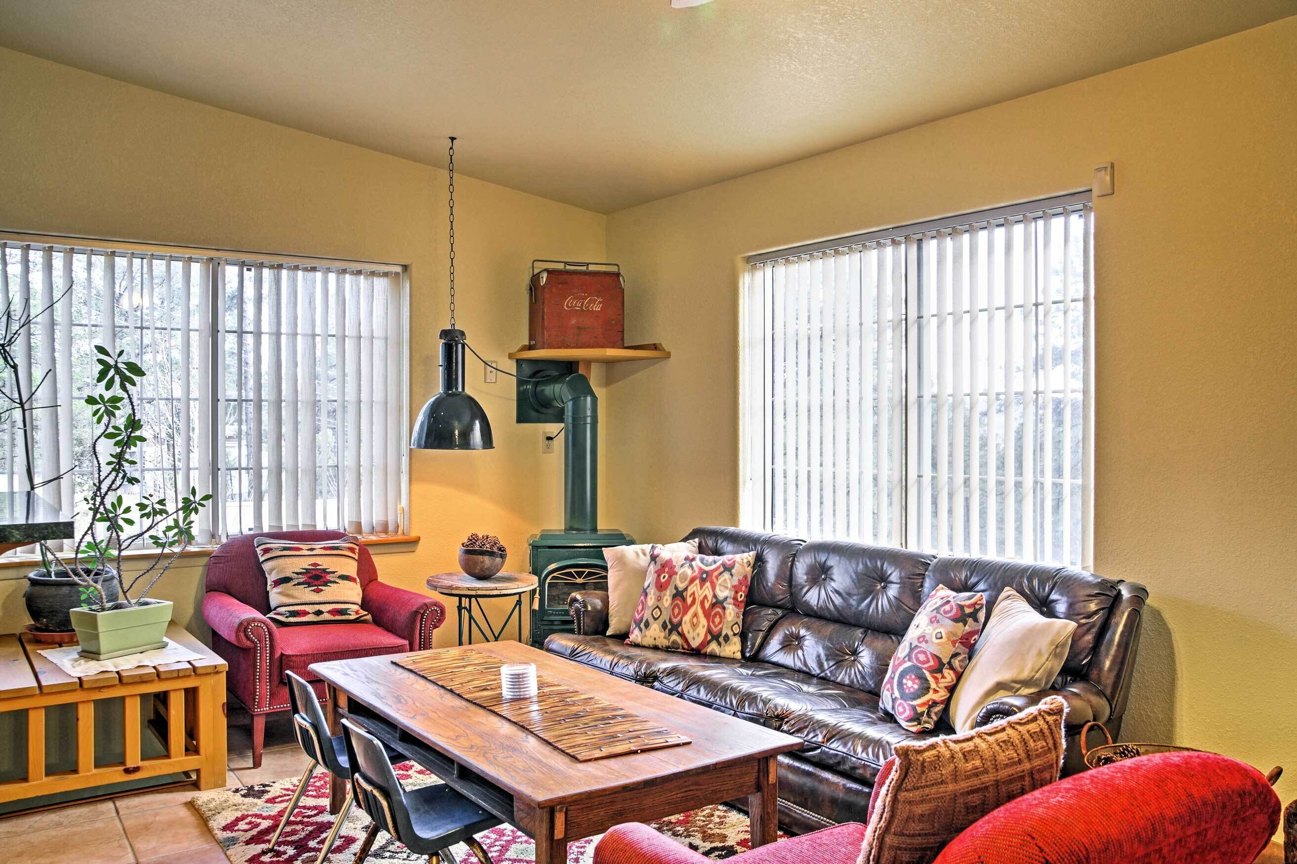 A cozy living room with a leather sofa, a wooden coffee table, and a red armchair. A vintage Coca-Cola cooler is mounted on the wall.