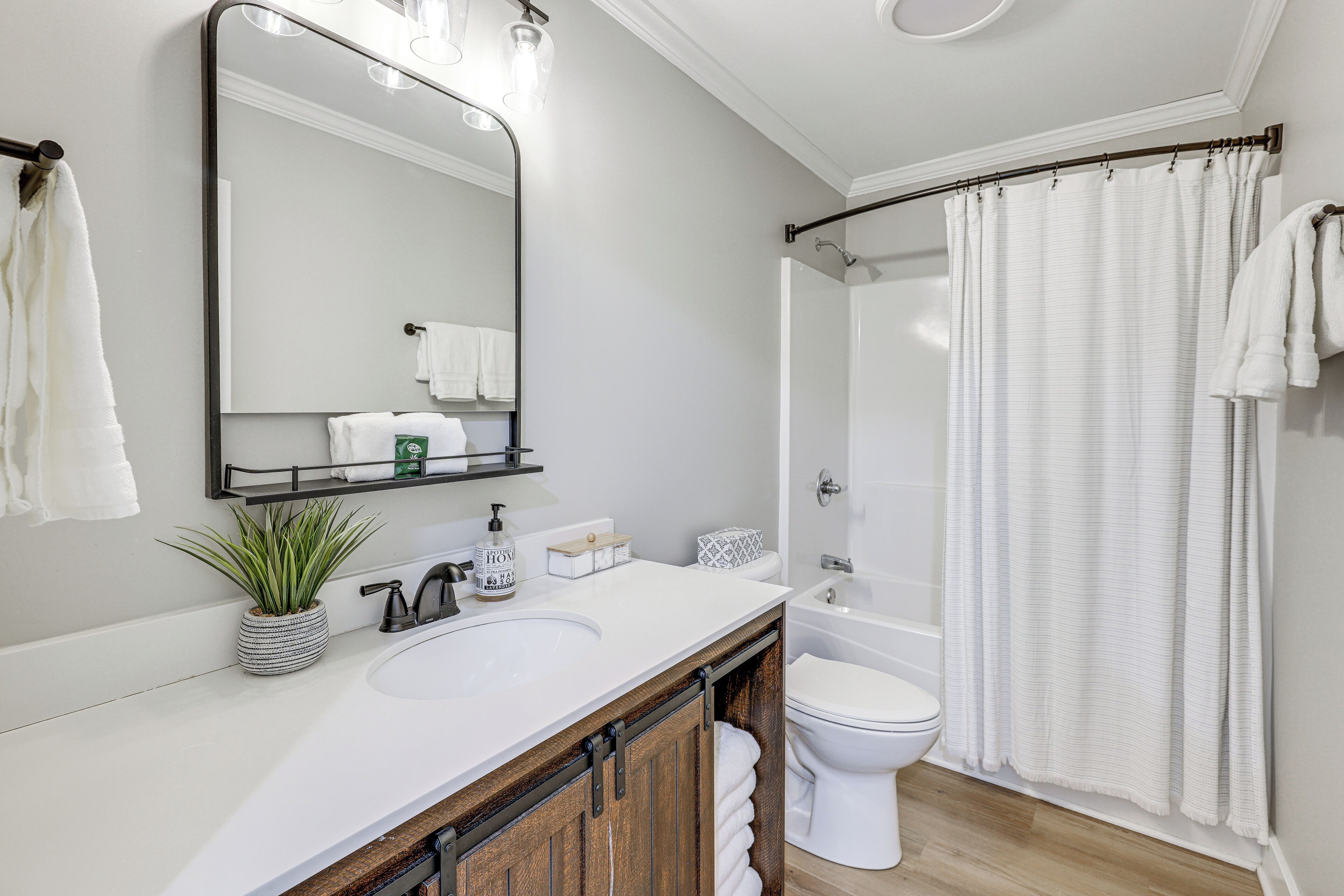 Un baño con lavamanos blanco, espejo, inodoro y cortina de ducha.