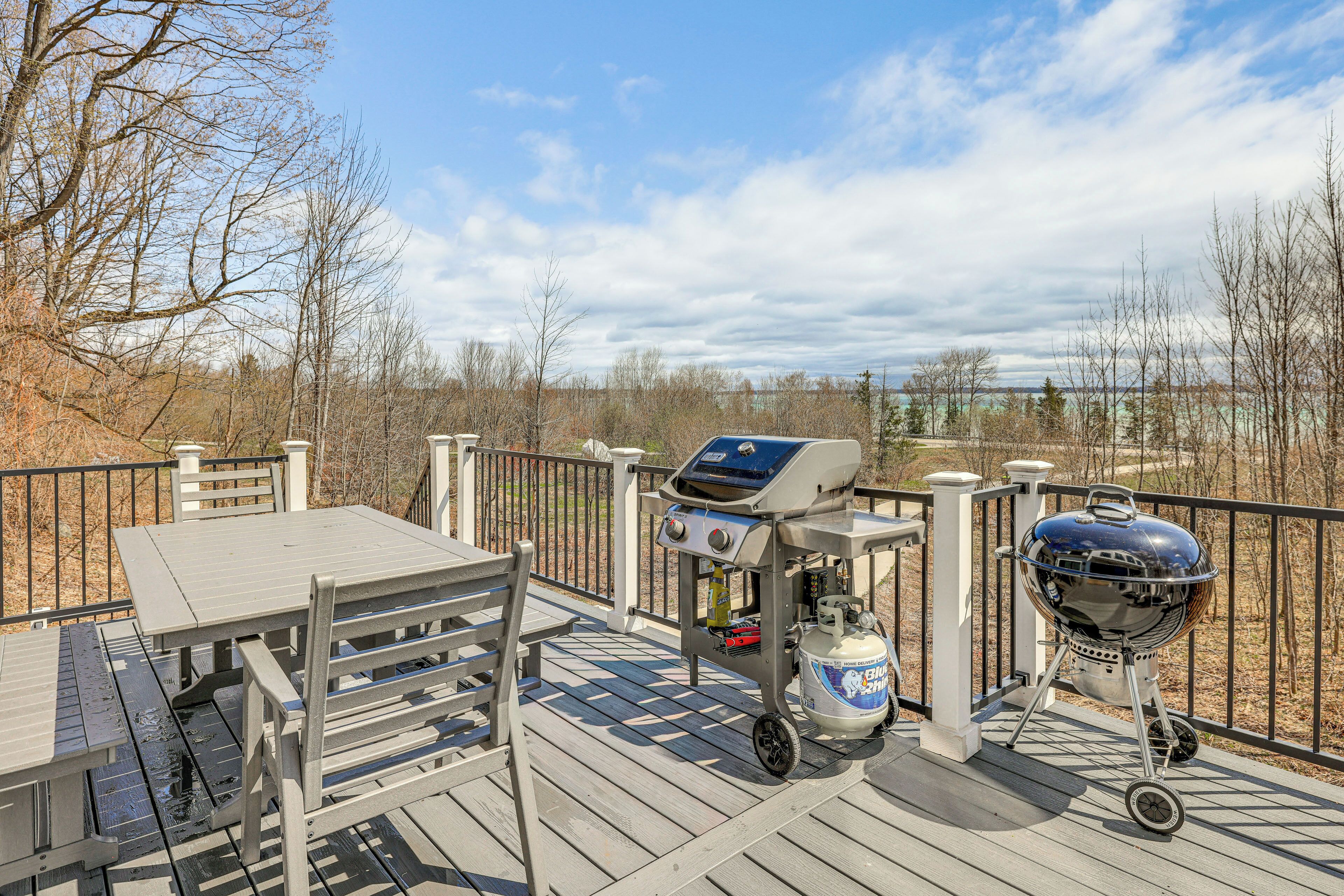 A deck with a grill, a table, and chairs.