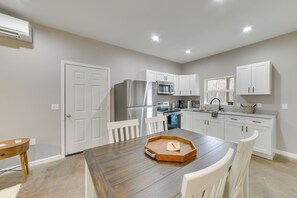 A modern kitchen with white cabinets, stainless steel appliances, and a wooden dining table. - Pet-friendly Murray Vacation Rental w/ Grill! (Murray)