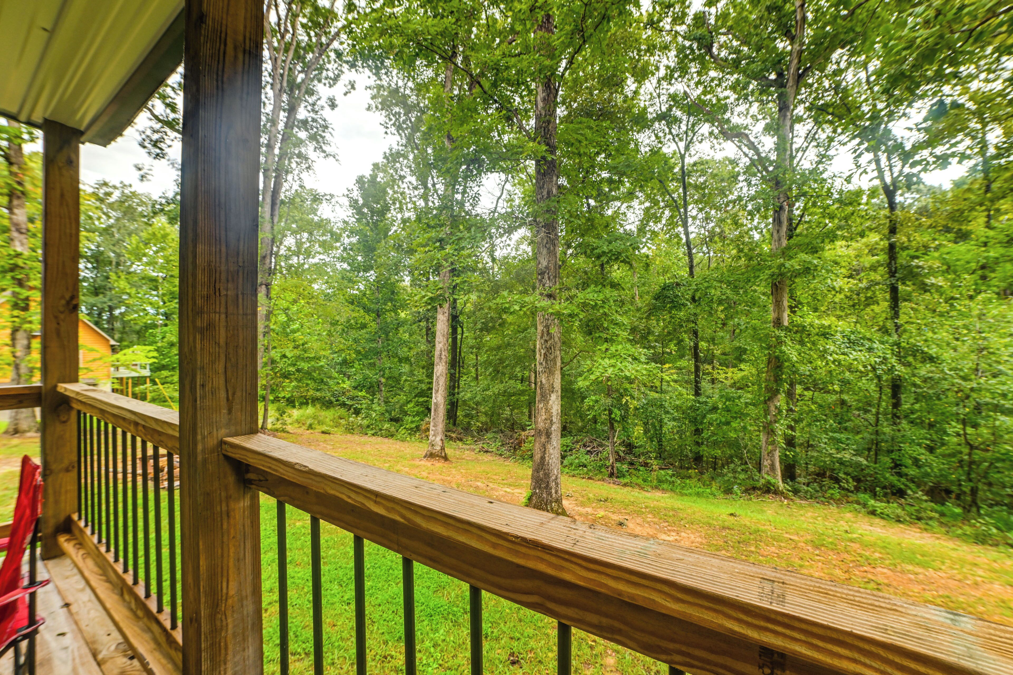A wooden deck with a railing overlooking a forested area.