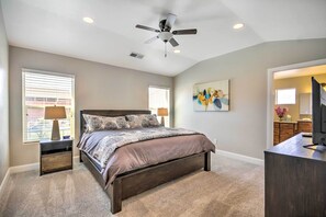 Une chambre à coucher avec un lit, des tables de chevet, un ventilateur de plafond et un téléviseur.