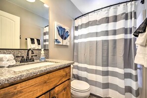 Une salle de bain avec un rideau de douche à rayures, un lavabo avec un robinet, des toilettes et un porte-serviettes avec des serviettes.