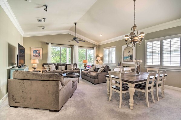A spacious living room with a large sofa, a dining table with chairs, and a ceiling fan. - Gulf Shores Condo on Golf Course w/ Resort Perks! (Gulf Shores)