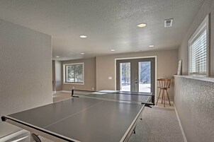 Una habitación con mesa de ping pong, una ventana y una puerta que da al exterior.