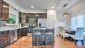 A modern kitchen with dark wood cabinets, stainless steel appliances, and a central island with bar stools. - Pond-view Deck + Pool Table: Woodbridge Haven! (Woodbridge)