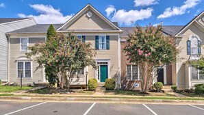A row of two-story townhouses with a green door, a brick section, and a parking lot in front. - Pond-view Deck + Pool Table: Woodbridge Haven! (Woodbridge)