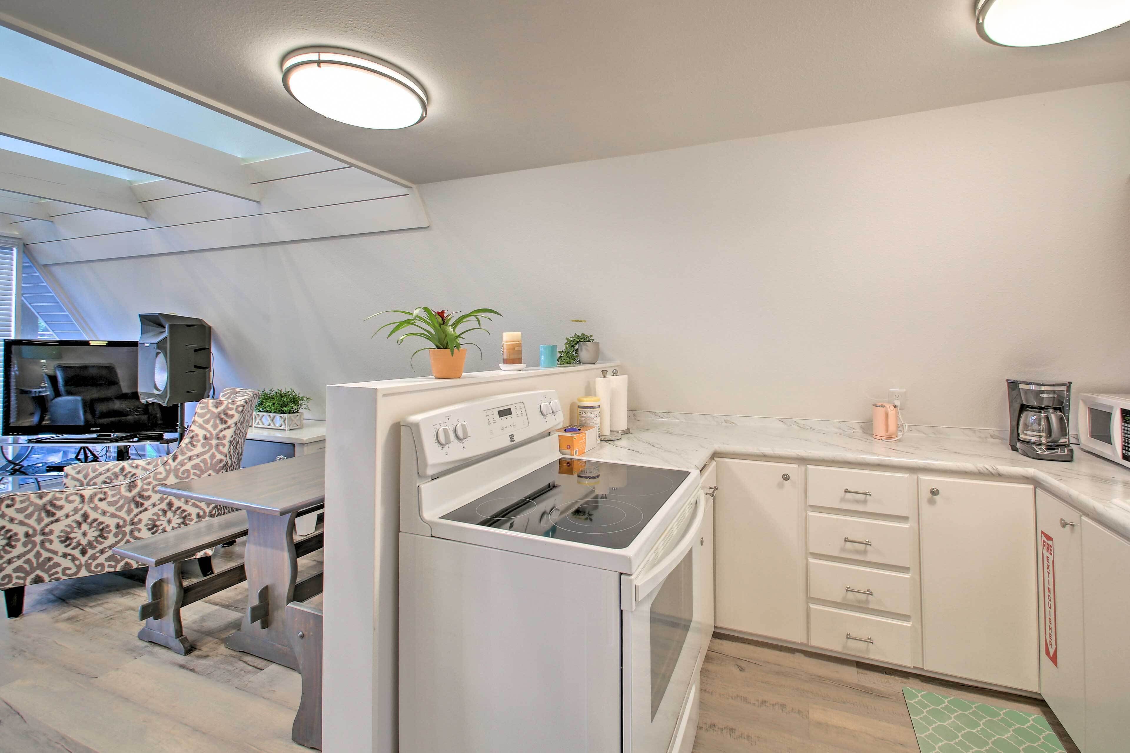 A modern kitchen with white cabinets, a built-in oven, and a dining area with patterned chairs.