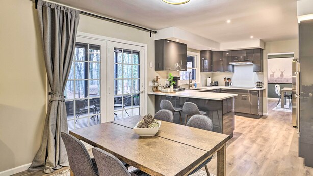 Una cocina moderna con una isla central, sillas grises y una mesa de comedor con un cuenco de objetos decorativos.