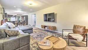 Una sala de estar moderna con un sofá seccional, un sillón de cuero, una mesa de centro de madera y una alfombra estampada.