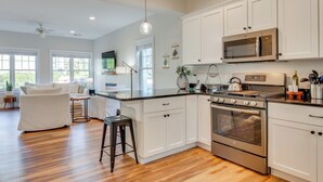 A modern kitchen with white cabinets, stainless steel appliances, and a wooden floor. - Stylish Arundel Cottage, 6 Mi to Dock Square! (Kennebunkport)