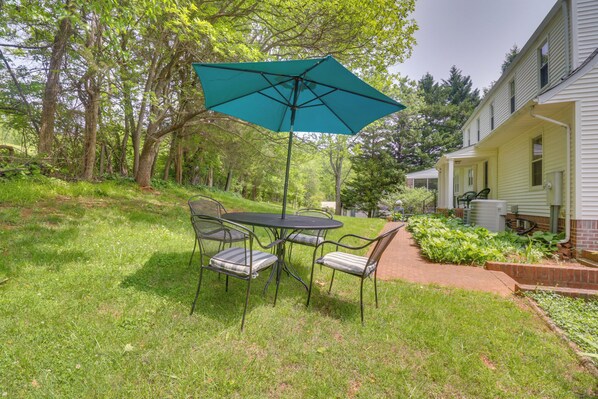 A patio with a table and chairs, a green umbrella, and a house in the background. - Rural and Spacious Virginia Home on ~ 2 Acres! (Orange)