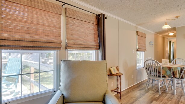 Una habitación con un ventanal grande, una silla, una mesa de comedor con sillas y una mesita auxiliar.