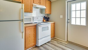 Una cocina con armarios de madera, un refrigerador blanco, una estufa y un microondas.