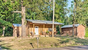 A wooden cabin with a porch, a garage, and a mailbox.