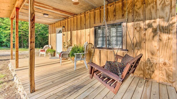 A wooden deck with a swing, chairs, and a table.