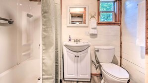A bathroom with a bathtub, a sink, a toilet, and a window.