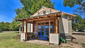 A small wooden cabin with a porch, a dining table, and a bench. - Spacious Glen Rose Home on Paluxy Riverfront (Glen Rose)