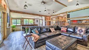 A spacious living area with a large leather sofa, a wooden coffee table, and a dining area in the background. - Spacious Glen Rose Home on Paluxy Riverfront (Glen Rose)