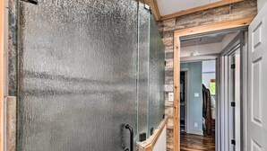 A hallway with a glass door leading to a room, wooden flooring, and a white door at the end. - Spacious Glen Rose Home on Paluxy Riverfront (Glen Rose)
