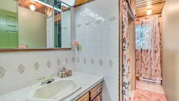 A bathroom with a white sink, mirror, and tiled walls.