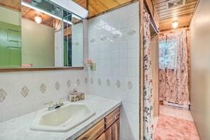 Een badkamer met een wit wastafelmeubel, spiegel en betegelde wanden.