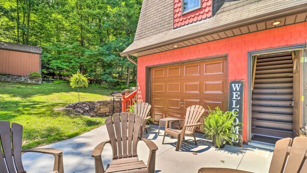 A red building with a garage door, outdoor seating with Adirondack chairs, and a 'WELCOME' sign. - Tamaqua Apartment w/ Fire Pit & Gas Grill! (Tamaqua)