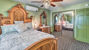 A bedroom with a wooden bed, a chandelier ceiling fan, a mirror, and a green door. - Tamaqua Apartment w/ Fire Pit & Gas Grill! (Tamaqua)