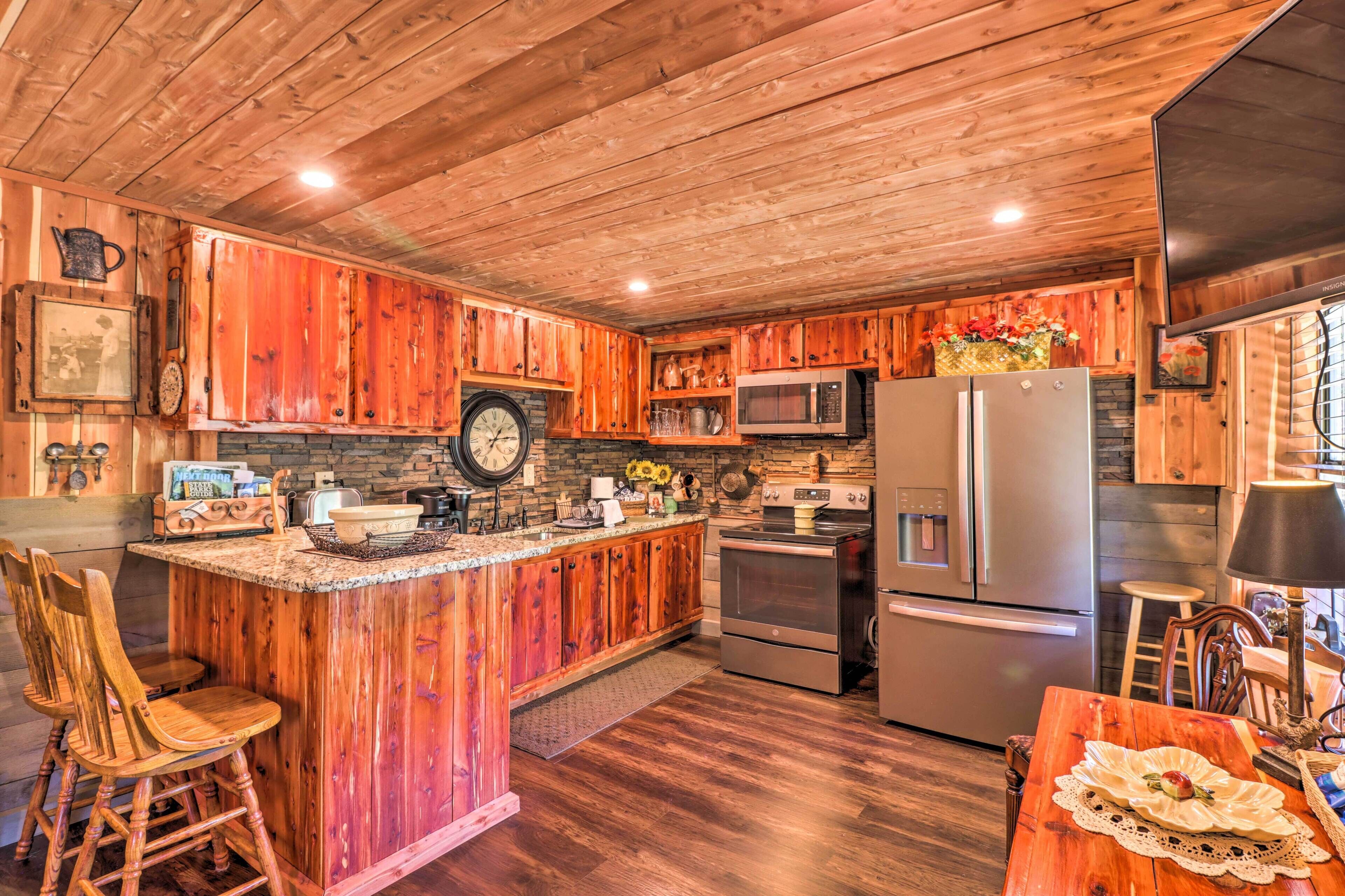 Une cuisine rustique avec des meubles en bois, un îlot central doté de tabourets de bar, des appareils électroménagers en acier inoxydable et une horloge au mur.