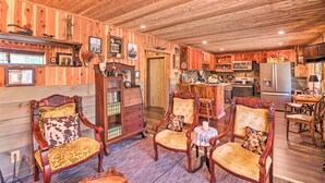 Un intérieur rustique en bois comprenant un coin repas, une cuisine et un espace détente avec des chaises d’époque.