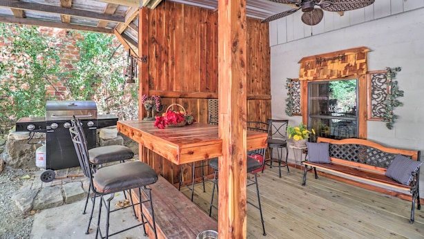 Une terrasse extérieure avec un barbecue en bois, une table en bois avec des chaises et un banc.