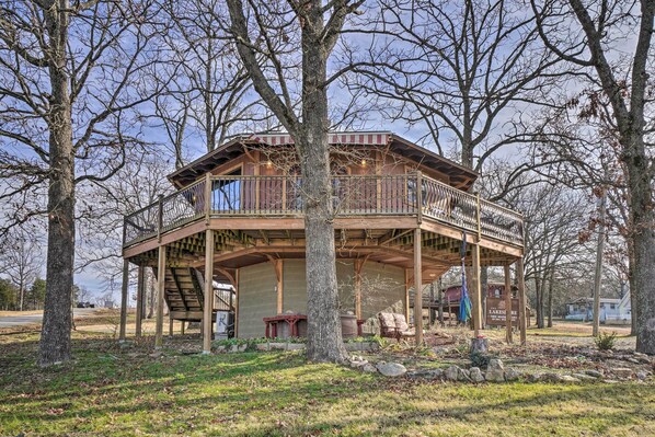 A wooden cabin with a balcony, surrounded by trees.