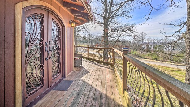 A wooden deck with a wrought iron gate and a wooden railing. - 'sunset Bluff Treehouse': On Bull Shoals Lake! (Lead Hill)