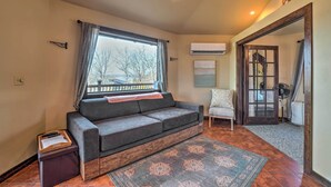 A cozy living room with a sofa, a small table with a tray, a patterned rug, and a view through a window. - 'sunset Bluff Treehouse': On Bull Shoals Lake! (Lead Hill)