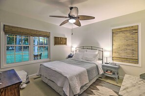 A bedroom with a bed, bedside table, lamp, and a ceiling fan.