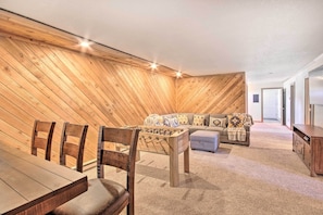 A cozy room with a wooden sloped ceiling, a foosball table, a sofa, and a dining table with chairs. - Stunning Gallatin Gateway Mountain Retreat! (Gallatin Gateway)