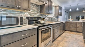 A modern kitchen with stainless steel appliances, dark wooden cabinets, and a tiled backsplash. - Welcoming Hattiesburg Home < 2 Mi to Usm! (Hattiesburg)