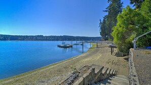 A lakeside view with a dock, boats, and a stone pathway leading to a wooden structure.