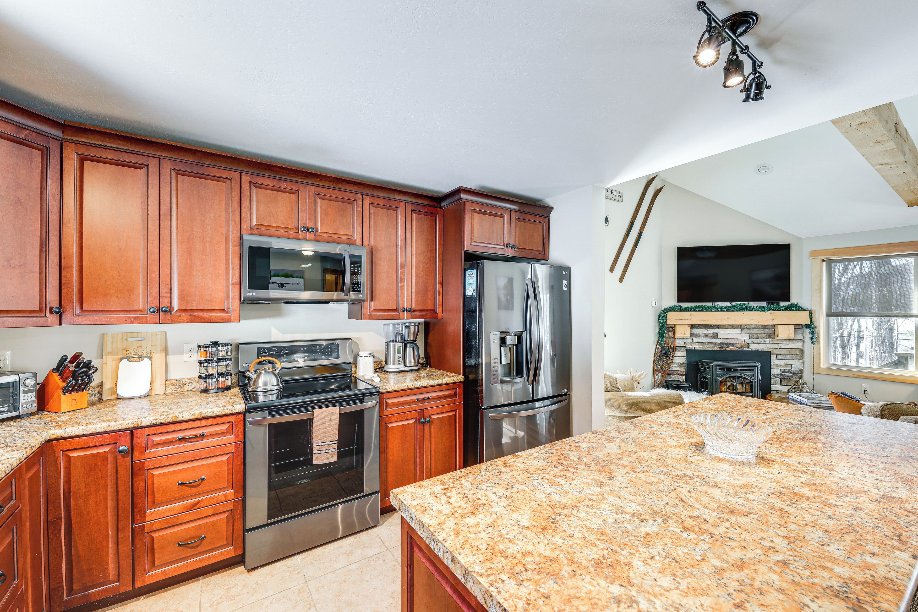 A kitchen with wooden cabinets, stainless steel appliances, granite countertops, and a fireplace.