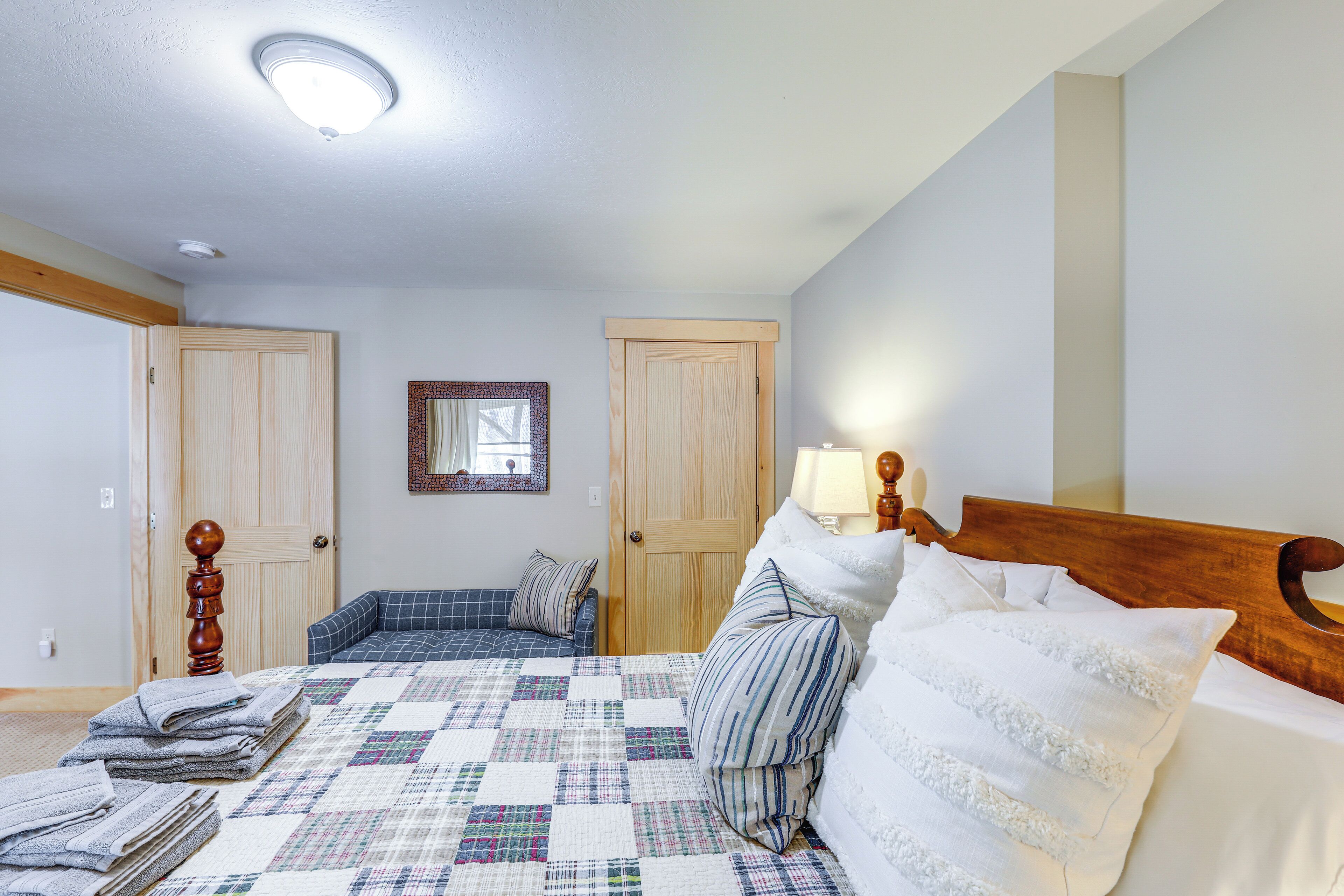 Ein Schlafzimmer mit einem Bett, einem Holz-Kopfteil, einer Steudecke und einem Nachttisch mit einer Lampe.