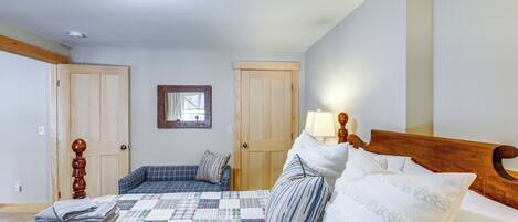 Ein Schlafzimmer mit einem Bett, einem Holz-Kopfteil, einer Steudecke und einem Nachttisch mit einer Lampe.