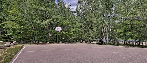 Uma quadra de basquete ao ar livre cercada por árvores.