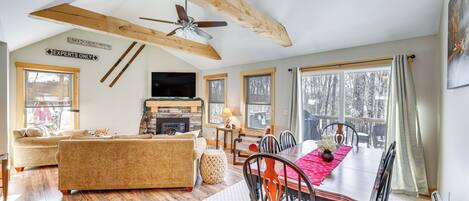 A spacious living area with a fireplace, a dining table, and a large window.