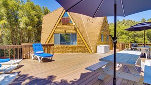 A wooden deck with blue lounge chairs and a picnic table, surrounded by trees. - 'star House' Unique Home w/ 360 Mountain Views! (Pine Mountain Club)