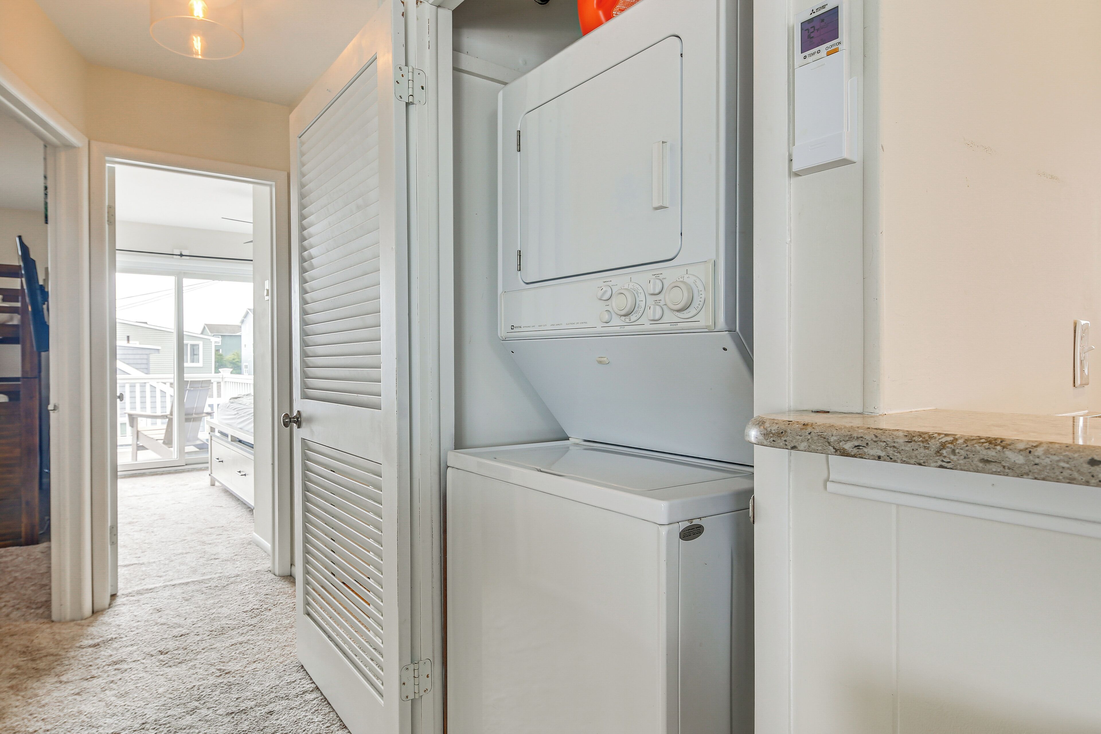 A laundry room with a washer and dryer, a countertop, and a door leading to a balcony.