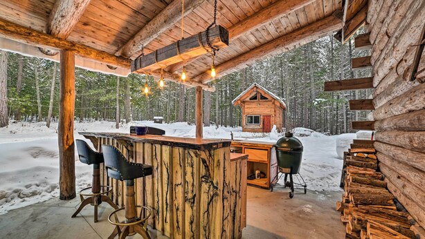 Een rustieke houten bar met uitzicht op een blokhut in een besneeuwd bos.