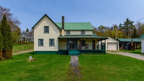 A two-story house with a green roof and a porch.